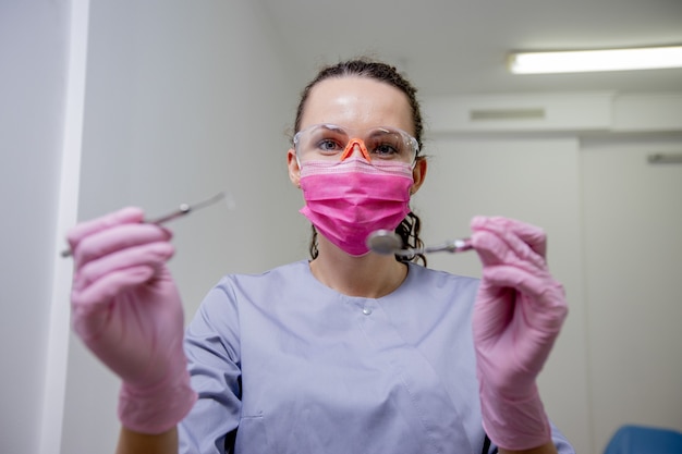 Retratos de uma mulher de dentista de profissão de aparência caucasiana com ferramentas nas mãos, o conceito de medicina.