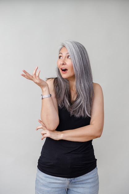 Foto retratos emocionales de una mujer madura asiática de pelo largo pálido en la pared gris