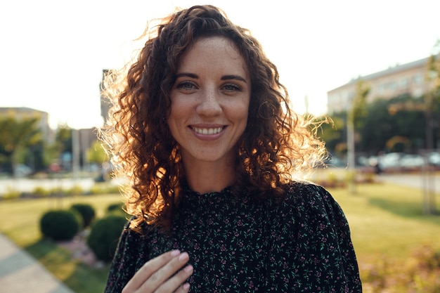 Retratos de una encantadora chica pelirroja con pecas y una cara bonita. La niña posa para la cámara en el centro de la ciudad. Ella tiene un gran humor y una dulce sonrisa.