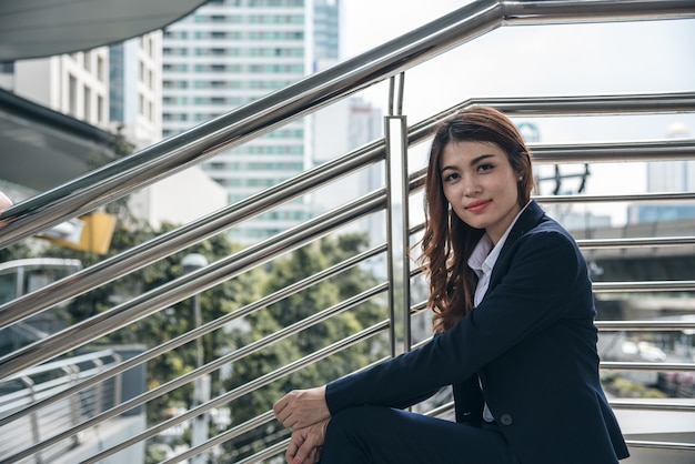 Los retratos de la mujer asiática hermosa parecen alegres y la confianza está sentada al aire libre