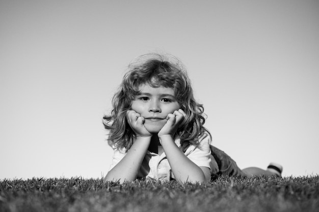 Retratos de niños felices jugando y tendido en el césped al aire libre en el parque de verano cara de niño gracioso al aire libre