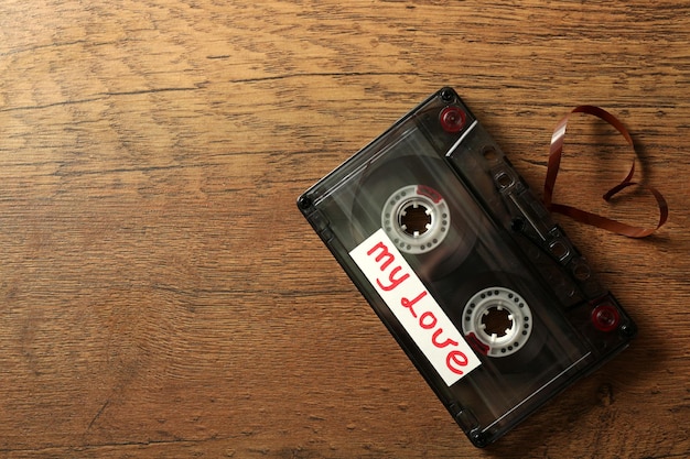 Retro-Audiokassette mit Band in Herzform auf Holzhintergrund