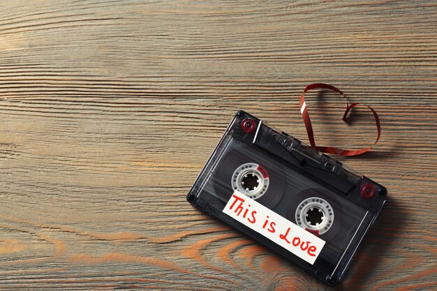 Retro-Audiokassette mit Band in Herzform auf Holzhintergrund