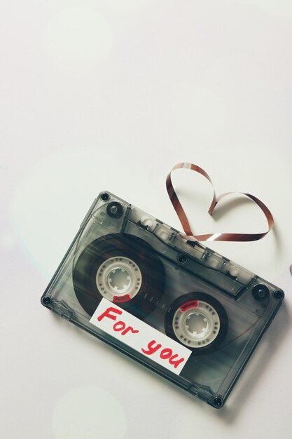 Retro-Audiokassette mit Band in Herzform auf weißem Hintergrund