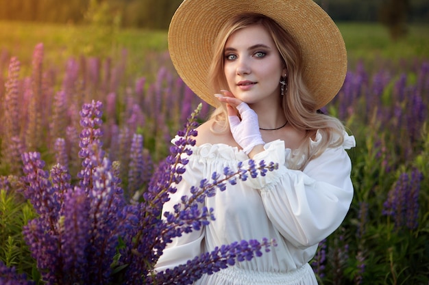 Retro-Dame genießt die Schönheit des blühenden LupinenbodensHarmony-Konzept Ein langes weißes Vintage-Kleid