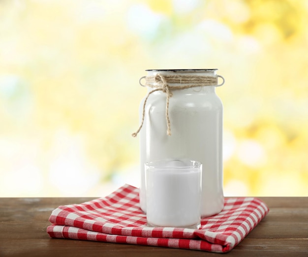 Foto retro-dose für milch und glas milch auf einem holztisch auf hellem hintergrund