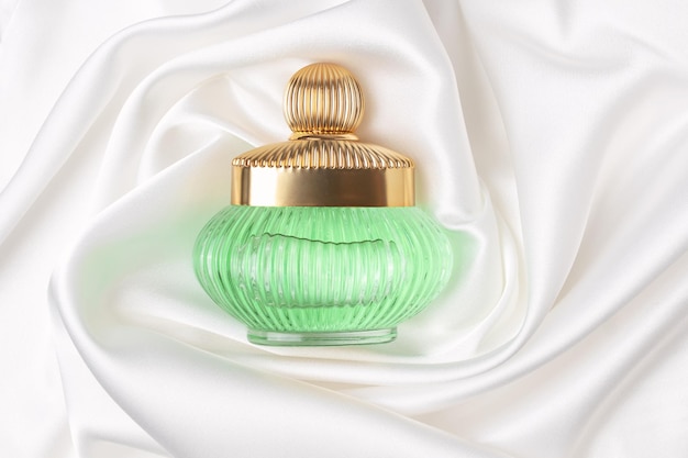 Retro-Duftflasche als Luxusparfümprodukt auf weißem Seidenhintergrund Konzept von teurem Parfüm und Kosmetik Blumiger Duft für Frauen Parfümspray