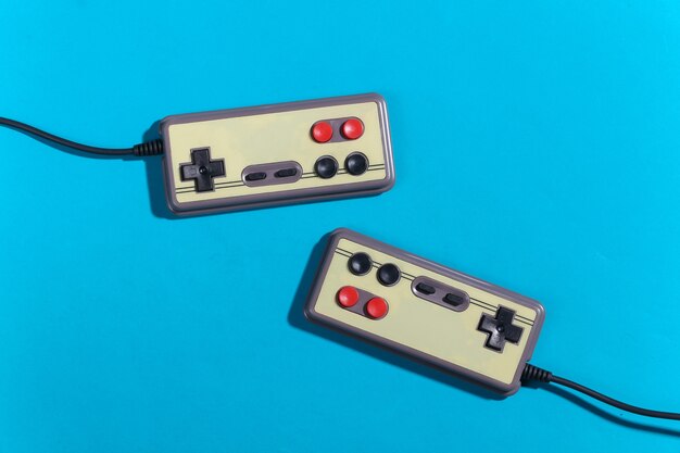 Retro-Gamepads auf blauem Hintergrund mit Schatten. Retro-Gaming. Ansicht von oben