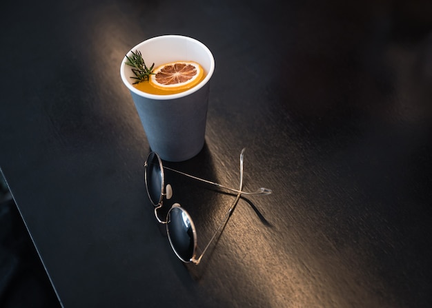 Retro Gläser mit orange Kaffee in Pappbecher auf Holztisch