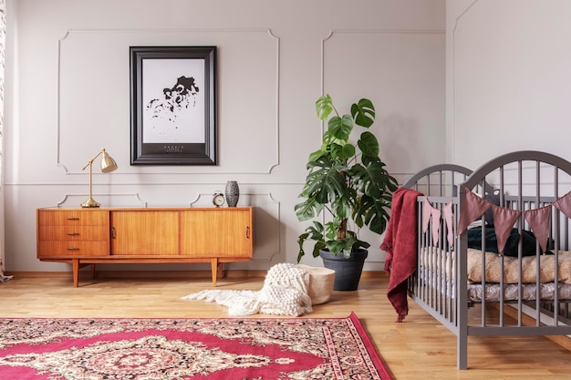 Retro-Holzschrank im grauen Kinderzimmer mit Monsterpflanze im schwarzen Topf