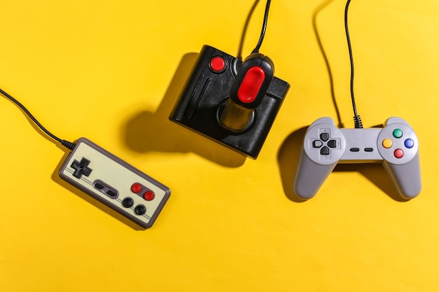 Retro-Joystick und Gamepads auf gelbem Hintergrund mit Schatten. Retro-Gaming. Ansicht von oben