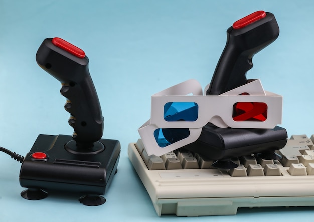 Retro-Joysticks mit alter PC-Tastatur und 3D-Brille. Blauer Hintergrund. Attribute 80er, Gaming