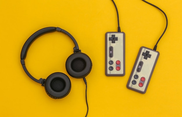 Retro-Joysticks und Kopfhörer auf gelbem Hintergrund. Spielen. Ansicht von oben