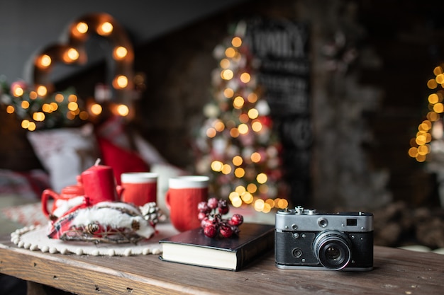 Retro-Kamera ist auf dem Tisch vor dem Hintergrund der Weihnachtslieder und Weihnachtsbäume