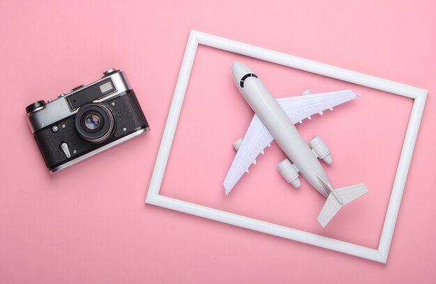 Retro-Kamera und Flugzeug in einem weißen Rahmen auf rosa Oberfläche