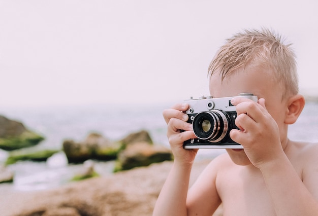 Retro- Kamerastrand des kleinen Jungen, der Fotos macht