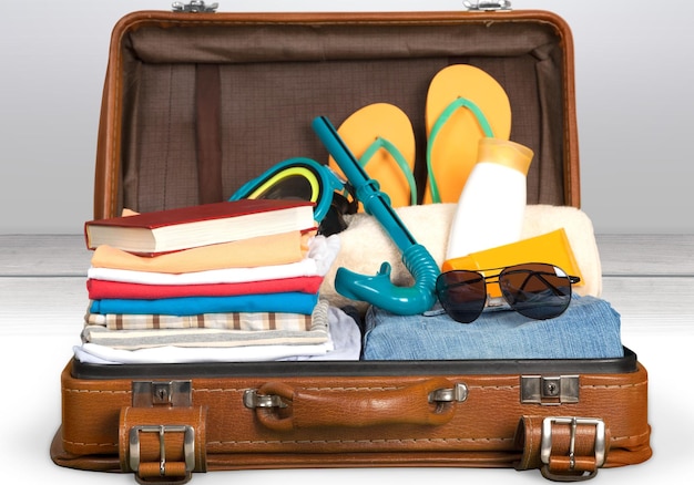 Retro-Koffer mit Reiseobjekten auf grauem Hintergrund
