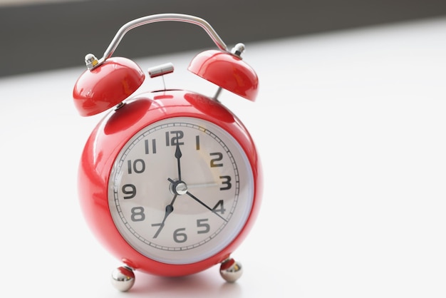 Retro-rote Uhr auf weißer Oberfläche zeigt sieben morgens Weckzeit für die Arbeit