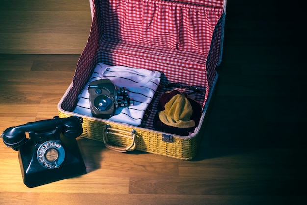 Retro- Taschen-Verpackungskamera gepaart mit älteren Telefonen auf hölzernem Hintergrund