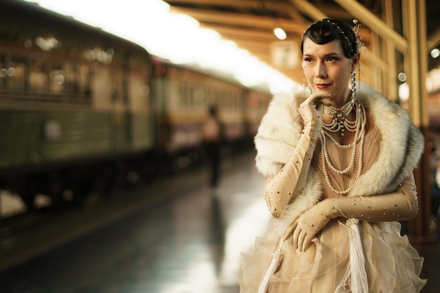 Retro-Vintage-Porträt der schönen Gatsby-Frau, schauen Sie sich um, warten Sie auf den kommenden Zug für den Liebhaber, fühlen Sie sich im romantischen Modestil der 20er Jahre am öffentlichen Bahnhof, Gatsby Old Fashion Concept