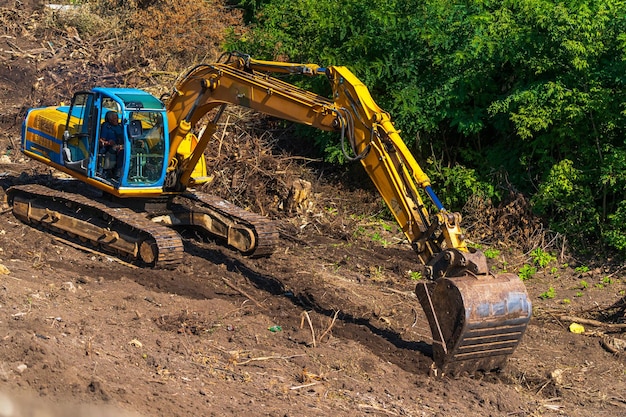 Retroescavadeira amarela com braço de pistão hidráulico Máquina pesada para escavação no canteiro de obras