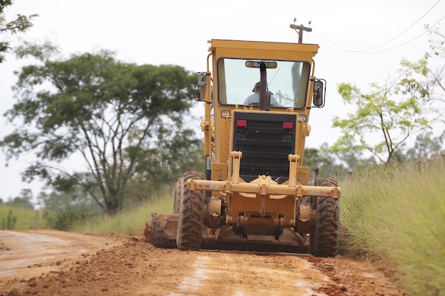 Retroescavadeira recuperando estrada de terra na área rural