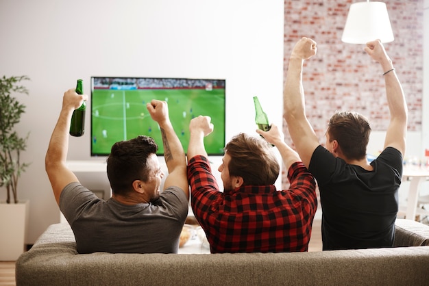 Foto retrovisor de homens assistindo a uma partida e torcendo por um jogo de futebol