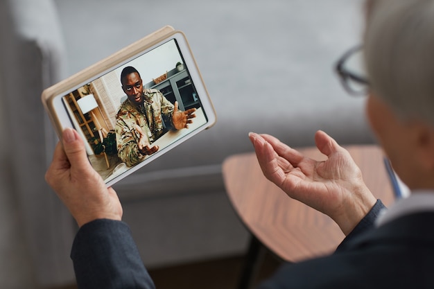 Retrovisor de mulher usando tablet digital para conversa online com soldado africano