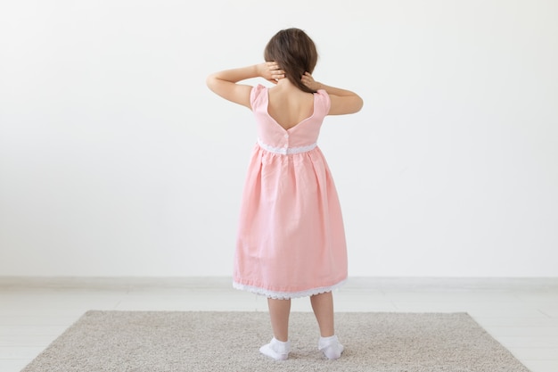 Retrovisor de uma encantadora princesa com um vestido rosa posando com um vestido de grife em uma superfície branca