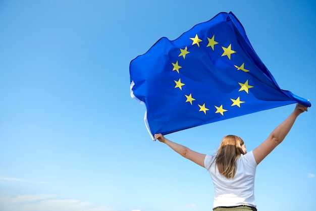 Foto retrovisor de uma jovem agitando a bandeira da união europeia