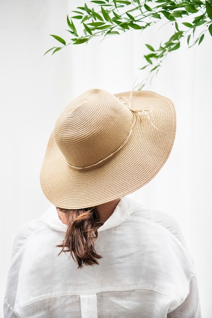 Retrovisor de uma mulher de cabelo castanho com um chapéu trançado