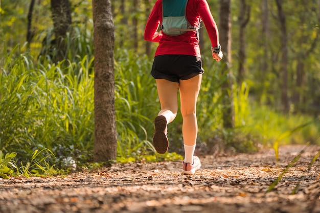 Foto retrovisor do corredor de trilha de mulher asiática adulta com colete de corrida pratica trilha correndo na floresta