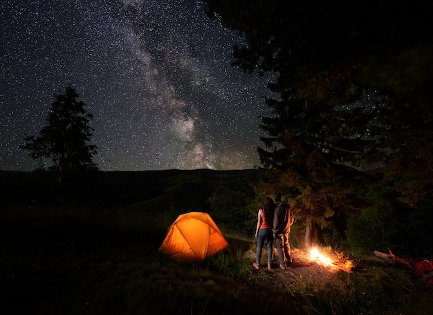 Retrovisor de una pareja de turistas jóvenes disfrutando del cielo estrellado.