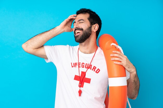 Rettungsschwimmer Mann über isolierte blaue Wand viel lächelnd