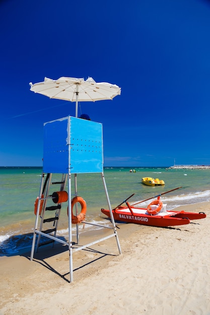 Foto rettungsschwimmerturm und roter katamaran am strand von italien