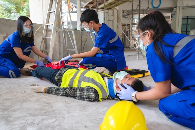 Rettungsteams helfen einem Bauarbeiter mit einem Unfall mit gebrochenem Bein auf einer Baustelle. Sicherheitsteam hilft bei Unfällen der Mitarbeiter.