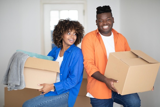 Reubicación del hogar feliz pareja negra cargando cajas de cartón en su nueva casa