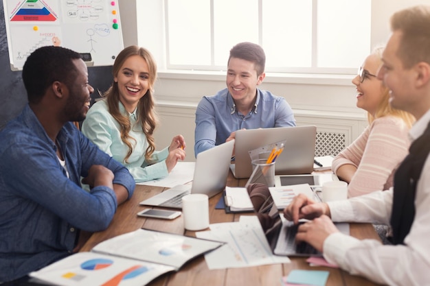 Reunião corporativa de negócios da equipe multiétnica. Jovens felizes e bem-sucedidos em um brainstorming, discutindo um novo projeto de inicialização no escritório, copie o espaço