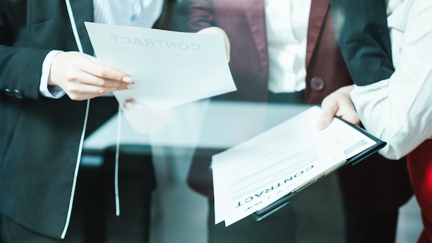 Reunião de advogados corporativos. Discussão de contrato de grande negócio. Executivas examinando o acordo.