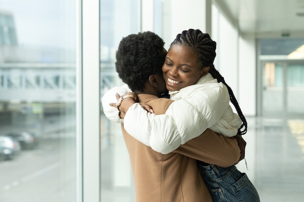 Reunião de casal no aeroporto. mulher africana conheceu o namorado do abraço, chegando após férias ou viagem ao exterior