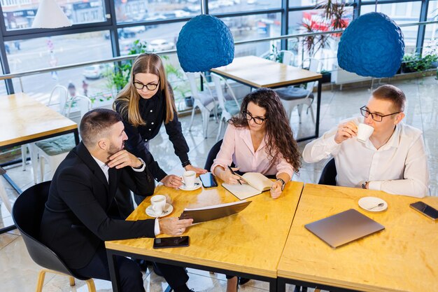 Reunião de empresários, discutindo novas idéias de negócios, usando diagramas, sentados juntos. Fundo de escritório moderno. Reunião de parceiros de negócios em uma conferência de desenvolvimento de negócios