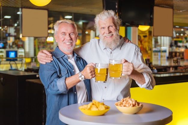 Reunião de familia. Homens simpáticos e felizes olhando para você em pé com copos de cerveja