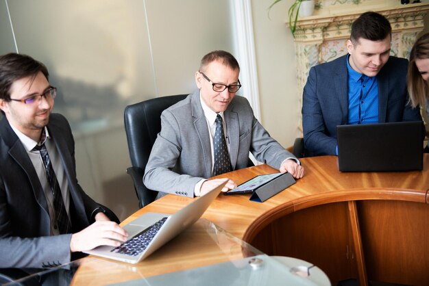 Foto reunião de mesa redonda de parceiros empresariais pessoas de negócios a falar e a usar portáteis e tablets