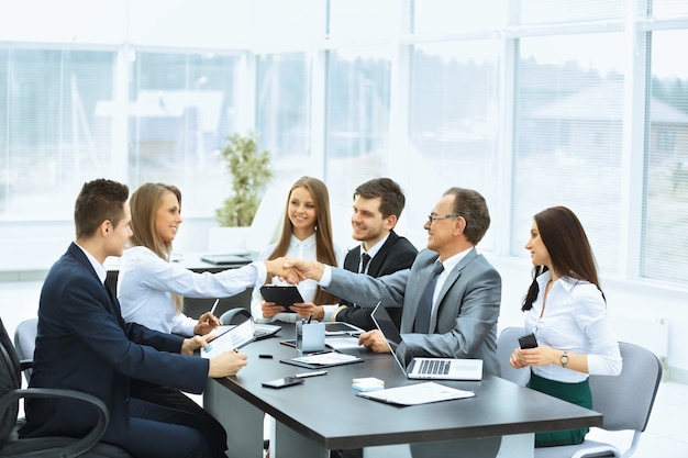 Reunião de negócios à mesa e aperto de mão de parceiros de negócios em um escritório moderno