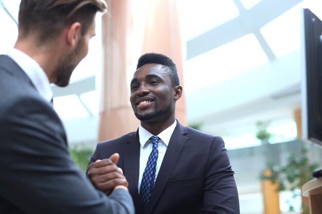 Reunião de negócios. Empresário americano africano apertando as mãos com empresário caucasiano.