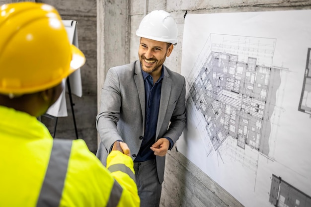 Reunião do canteiro de obras Engenheiro estrutural e aperto de mão do trabalhador e fazer um acordo no canteiro de obras