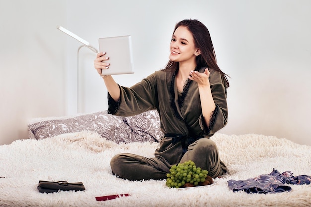 Reunião online usando tablet pc por mulher na cama com peles artificiais