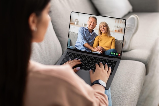 Reunião remota jovem mulher fazendo videochamada com pais idosos no laptop