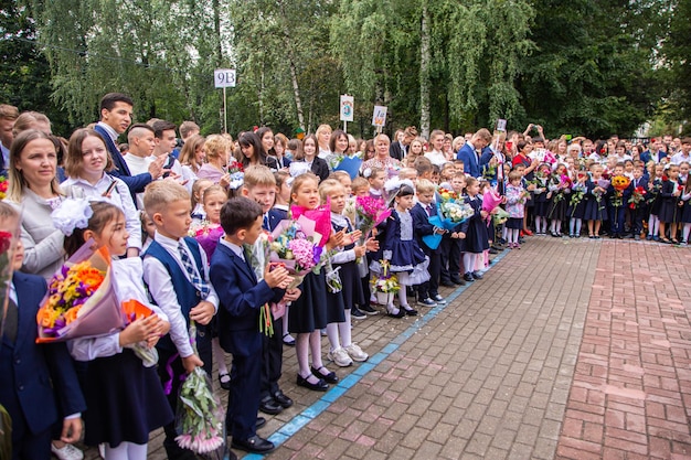Reunión con los alumnos de primer grado y el maestro en el patio de la escuela el día del conocimiento en Rusia