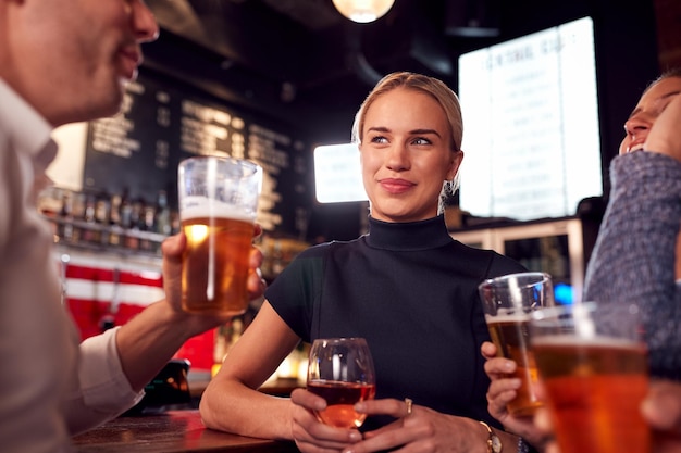 Reunión de amigos masculinos y femeninos para tomar una copa y socializar en el bar después del trabajo